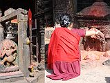 Kathmandu Valley 2 Kirtipur 06 Bagh Bhairav Temple Pilgrim And Statues Left Of Entrance A pilgrim makes offerings to the left of the entrance to the Bagh Bhairav Temple in Kirtipur near Kathmandu.